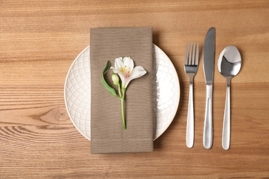 Flat lay composition with cutlery, plate and napkin on wooden background