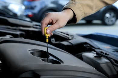 Man checking motor oil level in car with dipstick, closeup