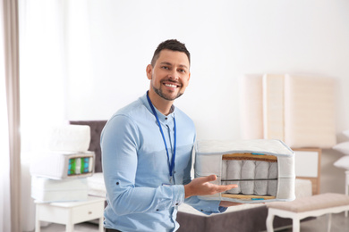 Salesman with section of mattress in furniture store