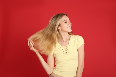 Portrait of beautiful young woman with blonde hair on red background