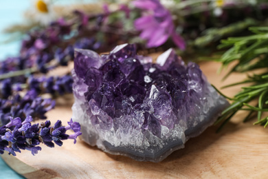 Amethyst and healing herbs on wooden board, closeup
