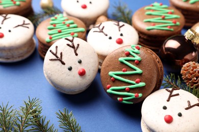 Photo of Beautifully decorated Christmas macarons on blue background, closeup