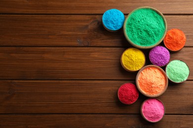 Colorful powder dyes on wooden background, flat lay with space for text. Holi festival