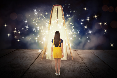 Woman and book with magic glowing on wooden surface. Fairy tale