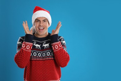 Excited man in Santa hat on blue background, space for text. Christmas countdown