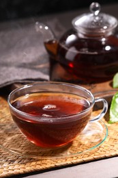 Photo of Aromatic hot tea in glass cup and teapot on table