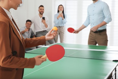 Business people playing ping pong in office, focus on tennis racket. Space for text
