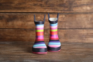Pair of striped rubber boots on wooden surface