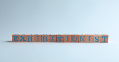 Word EXHIBITIONIST made with wooden cubes on white background