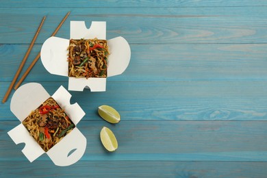 Boxes of wok noodles with vegetables, meat and chopsticks on light blue wooden table, flat lay. Space for text