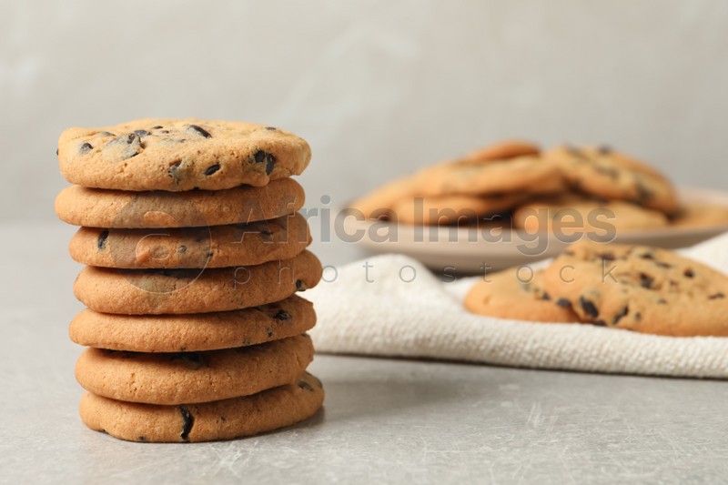 Stack of tasty chocolate chip cookies on grey table. Space for text