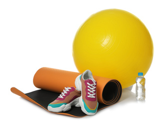 Fitness ball, yoga mat, bottle of water and sneakers isolated on white