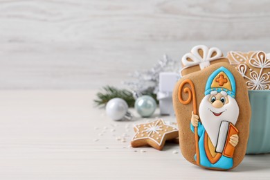 Tasty gingerbread cookies and festive decor on white wooden table, space for text. St. Nicholas Day celebration
