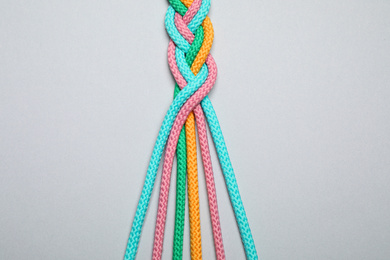 Braided colorful ropes on light grey background, top view. Unity concept