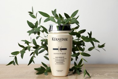 MYKOLAIV, UKRAINE - SEPTEMBER 07, 2021: Kerastase shampoo and green branches on wooden table. Hair care cosmetic product