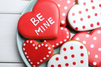 Decorated heart shaped cookies on white wooden table, top view. Valentine's day treat