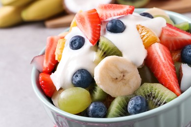 Delicious fruit salad with yogurt in bowl on table, closeup