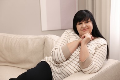 Beautiful overweight woman sitting on sofa at home