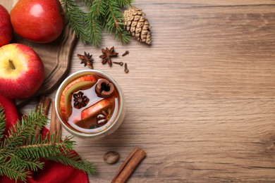 Hot mulled cider, ingredients and fir branches on wooden table, flat lay. Space for text