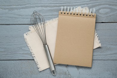 Photo of Blank recipe book and whisk on grey wooden table, flat lay. Space for text