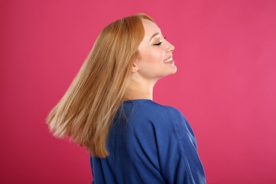 Beautiful young woman with blonde hair on pink background