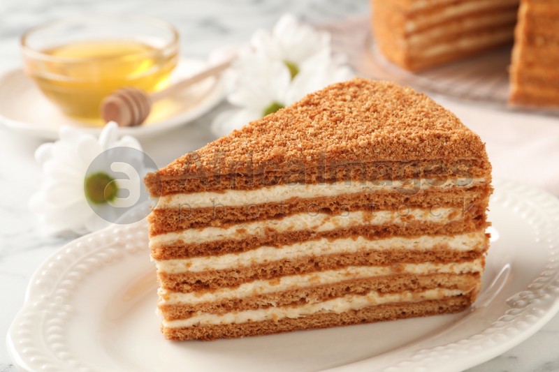 Slice of delicious layered honey cake served on white table, closeup