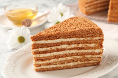 Photo of Slice of delicious layered honey cake served on white table, closeup