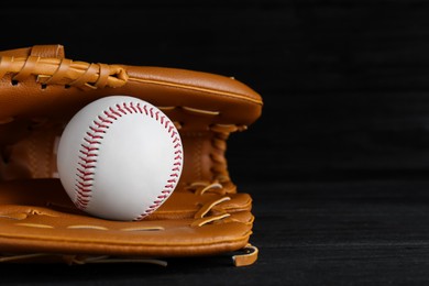 Photo of Catcher's mitt and baseball ball on black background, space for text. Sports game