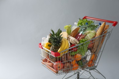 Shopping cart full of groceries on grey background. Space for text