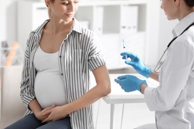 Doctor giving injection to pregnant woman in hospital. Vaccination concept