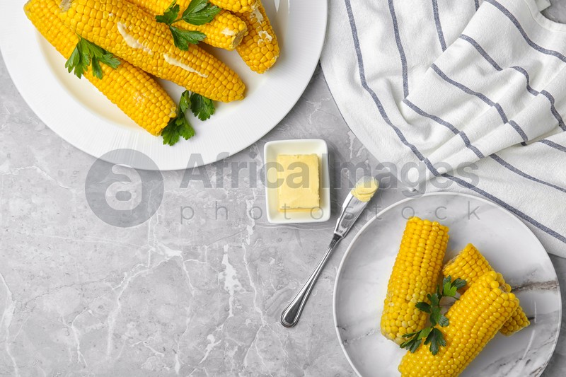Flat lay composition of boiled corn cobs on light grey marble table. Space for text