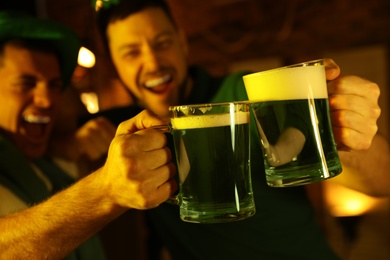 Men with beer celebrating St Patrick's day in pub, focus on hands