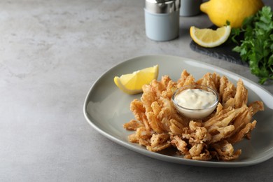 Fried blooming onion with dipping sauce served on grey table. space for text