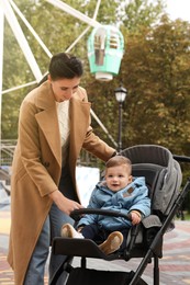 Happy mother walking with her son in stroller outdoors
