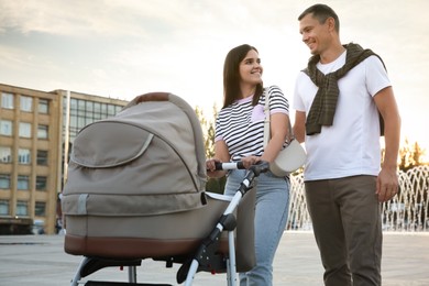 Happy parents walking with their baby in stroller outdoors