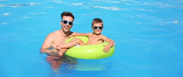Little boy on inflatable ring with happy father in swimming pool. Banner design