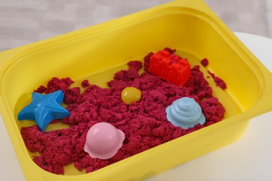 Bright kinetic sand and toys in yellow basin