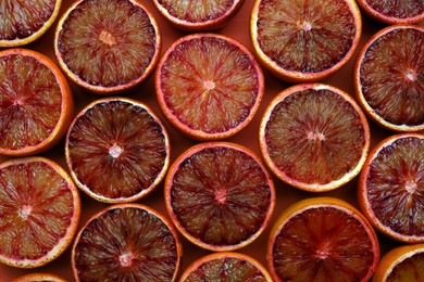 Slices of ripe sicilian oranges on red background, flat lay