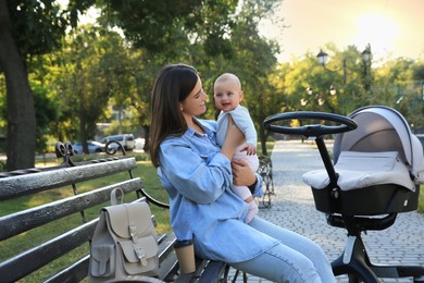 Young mother with her baby on bench in park