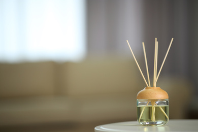 Photo of Aromatic reed air freshener on table indoors. Space for text