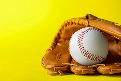 Photo of Catcher's mitt and baseball ball on yellow background, space for text. Sports game