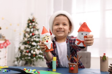 Cute little child with beautiful Christmas crafts at table in decorated room