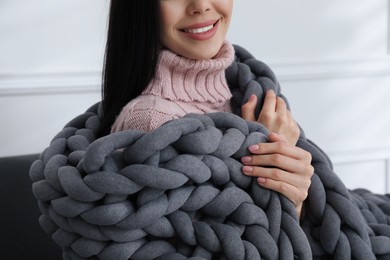 Woman with chunky knit blanket at home, closeup