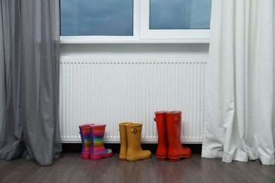 Rubber boots near heating radiator in room
