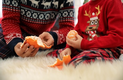 Father and little daughter peeling tangerines on faux fur, closeup