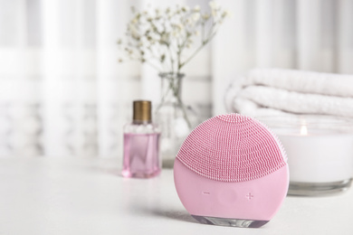 Modern face cleansing brush on white table. Cosmetic accessory
