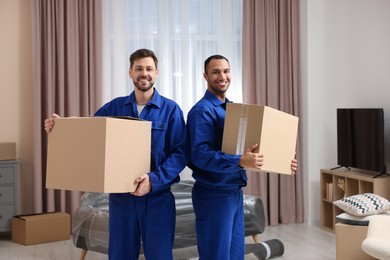 Photo of Male movers with cardboard boxes in new house