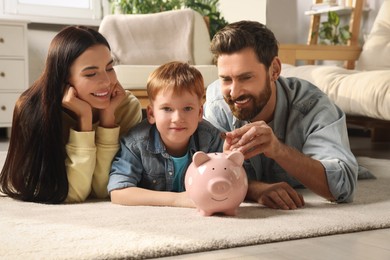 Happy family with ceramic piggy bank on floor at home