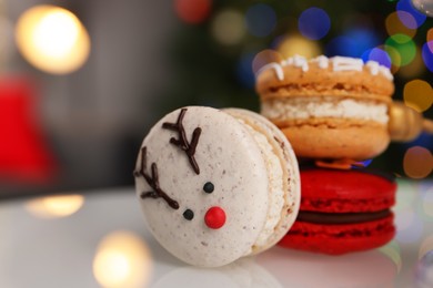 Photo of Beautifully decorated Christmas macarons on white stand against blurred festive lights, closeup