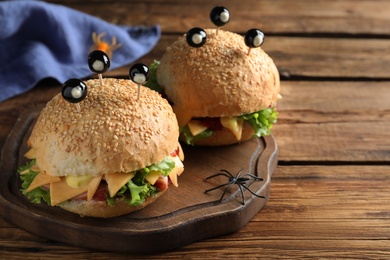 Cute monster burgers served on wooden table. Halloween party food